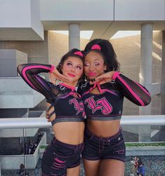 two women in black and pink outfits posing for the camera with their arms around each other