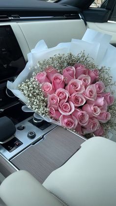 a bouquet of pink roses sitting on top of a white car seat next to a radio