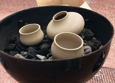 three vases sitting on top of rocks in a bowl