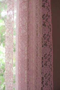 pink lace curtains hanging in front of a window