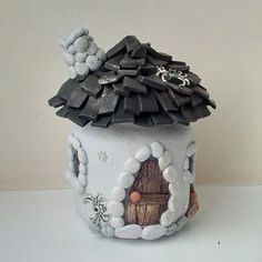 a small ceramic pot with a house on it