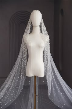 a mannequin wearing a white wedding veil on top of a dress form with pearls