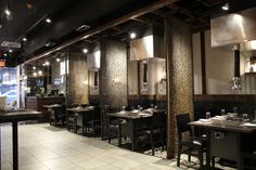 an empty restaurant with tables and chairs in front of the wall, along with mirrors on the walls