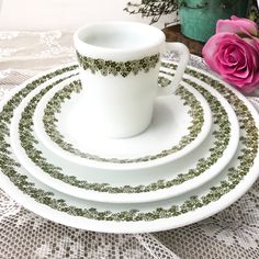 a set of four white and green dinnerware with floral designs on the rims