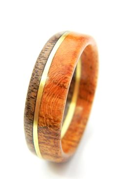 a wooden ring with gold inlays on the outside and inside, against a white background