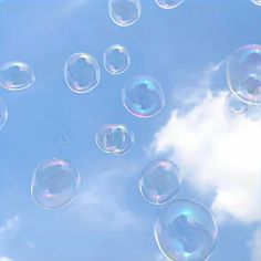 soap bubbles floating in the air on a sunny day with blue sky and clouds behind them