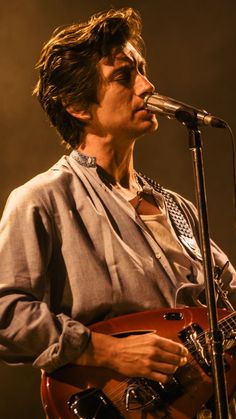 a man holding a guitar while standing in front of a microphone