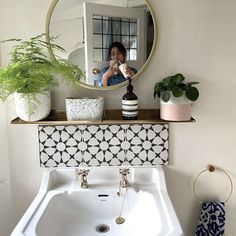 a bathroom sink sitting under a mirror next to a potted plant on top of a counter