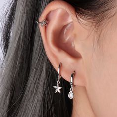 a close up of a person's ear wearing silver earrings with flowers on them