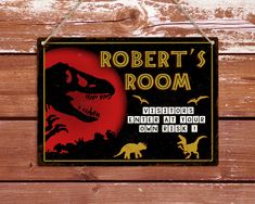 a sign that says robert's room on the side of a wooden wall with dinosaurs