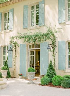 a large house with blue shutters and potted plants in front of the door