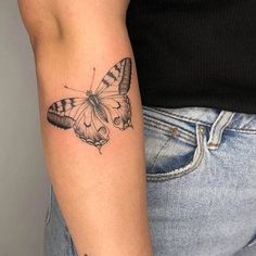 a woman's arm with a butterfly tattoo on the left side of her arm