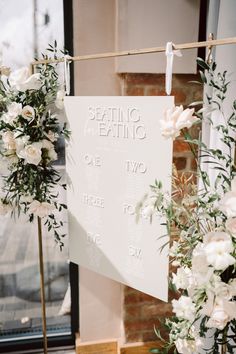 the seating sign is set up with flowers and greenery