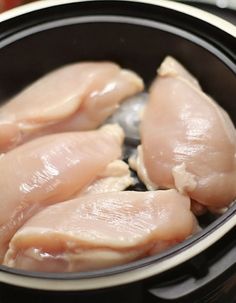 three pieces of raw chicken in a slow cooker