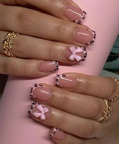 a woman's hands with pink and black nail polishes on their nails, holding a coffee cup