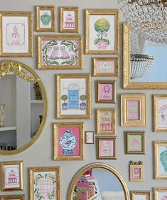 a wall covered in lots of framed pictures next to a mirror and chandelier