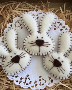 four decorated cookies in the shape of bunnies on a lace doily with straw