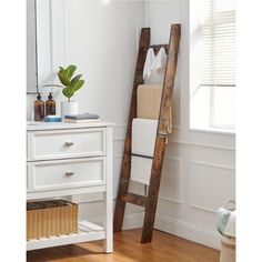 a wooden ladder leaning up against a white wall in a bathroom next to a mirror