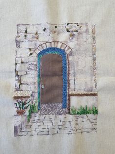 an embroidered piece of cloth with a door and potted plants on the outside wall