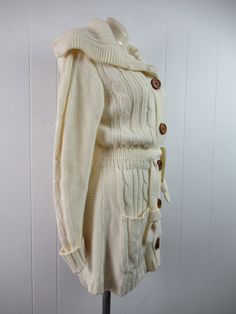 "Vintage 1970s sweater. Made of Acrylic knit. Color is cream white. Bohemian hippy style. Has a button down front, wooden buttons, large cowl style collar, internal cinches waist belt and two lower pockets. Made by F.O.B./ N.Y. About a size medium. Actual measurements are: 36\" at the bust 29\" at the waist 39\" at the hips 15.5\" shoulder seam to shoulder seam 28\" shoulder seam to cuff(with cuffs not rolled up) 33\" overall length In excellent condition." Cream Long Sleeve Sweater Coat With Buttons, Cozy Cream Sweater Coat With Buttons, Bohemian Winter Sweater With Buttons, Bohemian Winter Cardigan With Buttons, 1970s Sweater, Hippy Style, Bohemian Sweater, White Bohemian, Womens Sweaters