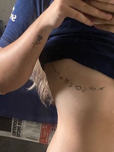 a woman is looking at her cell phone while she has tattoos on her stomach and back