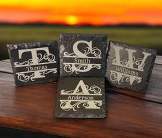 three slate coasters sitting on top of a wooden table with the sun setting in the background