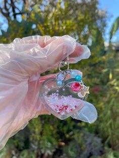 a hand holding a heart shaped keychain with pink and blue beads on it