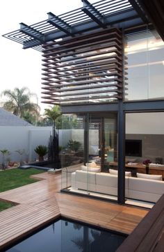 an outdoor living area with wooden decking and glass walls