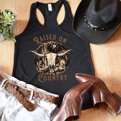 Show your inner cowgirl in this cute country cow skull tank. A great tank top while rockin' out at your favorite country concert. An awesome gift for your best friend or favorite country girl. All of our tank tops are printed on the Next Level 1533 racerback tank. This racerback cut looks good on any woman's shoulders. It's soft and comfortable and is made from 60% combed ring-spun cotton, 40% polyester. The fabric has a subtle luxurious feel, making it pleasant to touch. Made from specially spu Country Tank Tops Women, Black Western Tops For Summer, Western Style Tops For Summer Western-themed Events, Cotton Skull Print Sleeveless Tank Top, Black Western Style Summer Tops, Western Style Tops For Summer Western Events, Black Western Style Tops For Summer, Cotton Sleeveless Tank Top With Skull Print, Summer Skull Print Tank Top