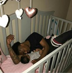 a woman laying in a crib with a baby next to her and hearts hanging from the ceiling