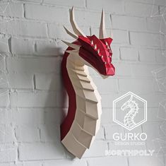 a red and white dragon head mounted to the side of a brick wall with geometric shapes