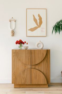 a wooden cabinet sitting next to a potted plant on top of a hard wood floor