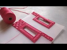 two pieces of pink thread sitting on top of a white surface next to a spool of yarn