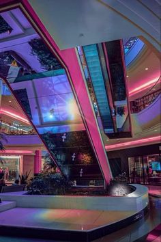 the interior of a shopping mall with pink and blue lighting on the ceiling, stairs and windows