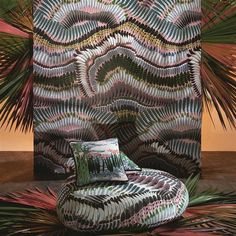 a chair sitting in front of a wall covered with plants and leaves on top of a wooden floor