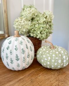 two painted pumpkins sitting on top of a wooden table