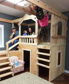 children are playing in a wooden play house with stairs and ladders to the second floor