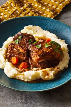 a blue plate topped with meat and mashed potatoes