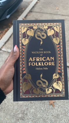 a person holding up a book in front of their face and the words african folklore written on it