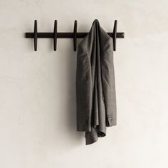 a coat rack with two coats hanging from it's sides and a pair of pants hanging on the wall