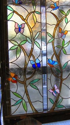 a stained glass window with flowers and leaves on it's sides, in the corner of a room