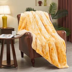 a chair with a blanket on top of it in front of a table and lamp