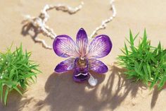 A perfect touch for any nature lover..... Dendrobium Orchid preserved in hand-layered resin. This charm necklace is made with high-quality clear resin and soft-touch finishes. Carefully sanded and polished by hand. The petals have a gradient effect, with deep purple on the edges transitioning to a pale purple towards the center, featuring delicate pink and blue veins. The intricate details of the flower's structure are visible, showcasing its natural beauty within the resin. The pendant measures Purple Jewelry Necklace, Blue Veins, Dendrobium Orchid, Flower Structure, Orchid Necklace, Tropical Jewelry, Dendrobium Orchids, Orchid Purple, Pale Purple