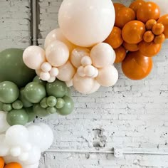 several balloons are hanging from the ceiling in front of a white brick wall with orange and green accents