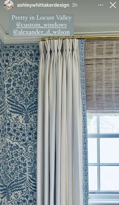 the curtain is hanging in front of a window with blue and white wall paper on it