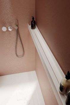 a shower head and hand held shower faucet in a bathroom with pink walls