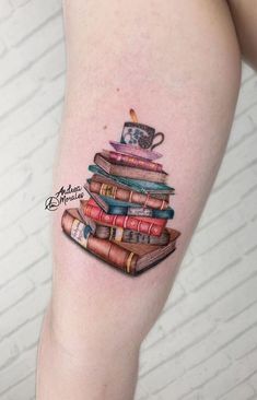 a stack of books with a cup on top of it tattoo by artist adam schneck