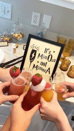 several people holding up drinks in front of a sign