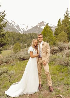 a bride and groom posing for a photo in the mountains