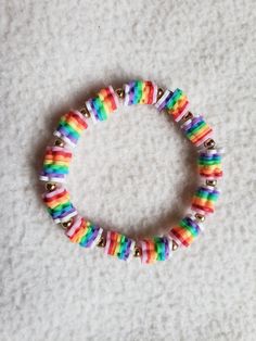 a bracelet with multicolored beads and gold bells on it sitting on a white surface